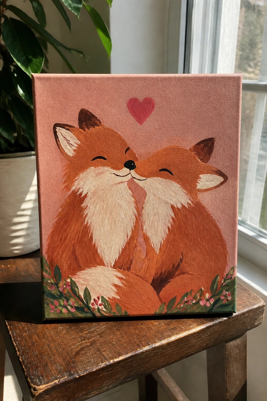 Two foxes nuzzling noses under a pink heart on floral pink canvas