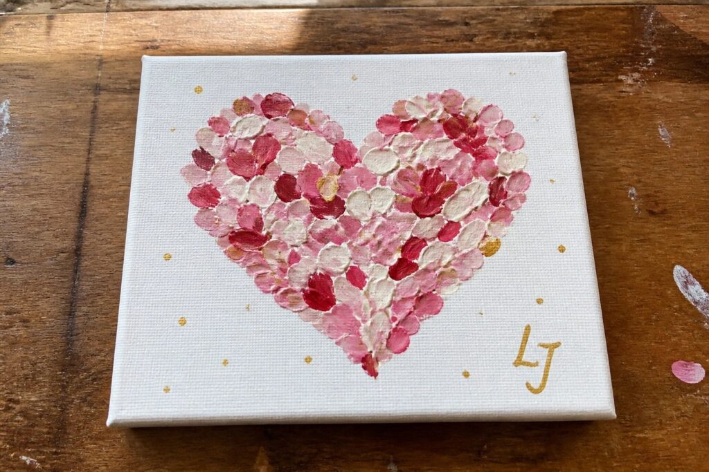 Pink heart of layered brushstrokes with gold dots and K+M on canvas