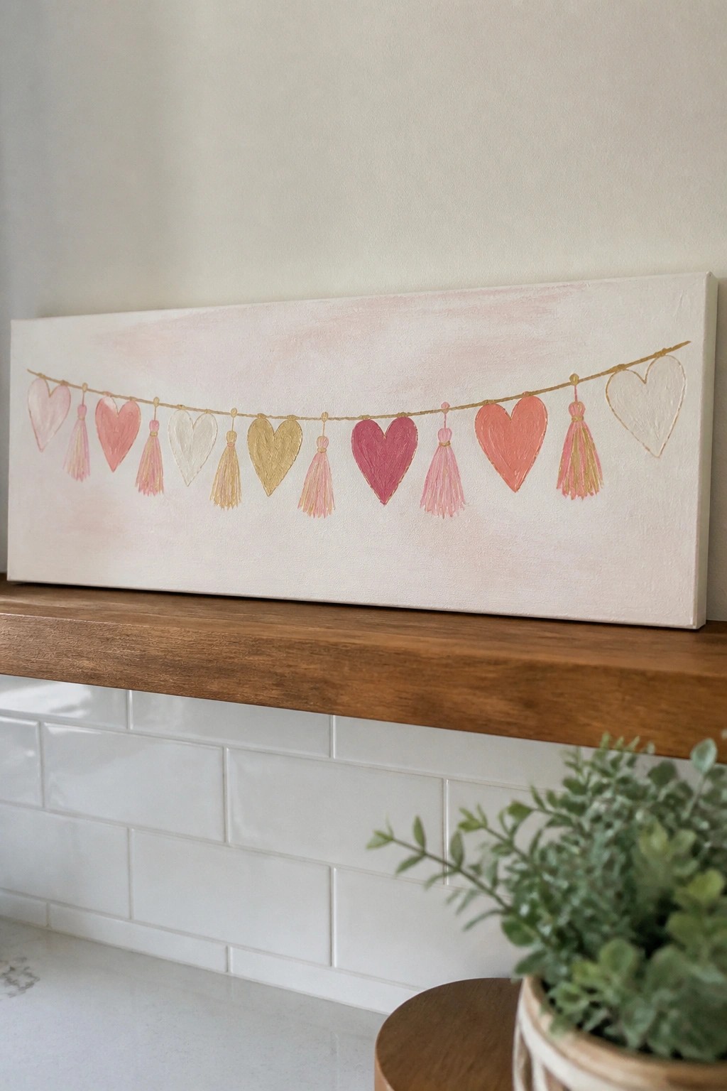 Pink and gold heart tassel garland painted on canvas above wooden shelf and tiles