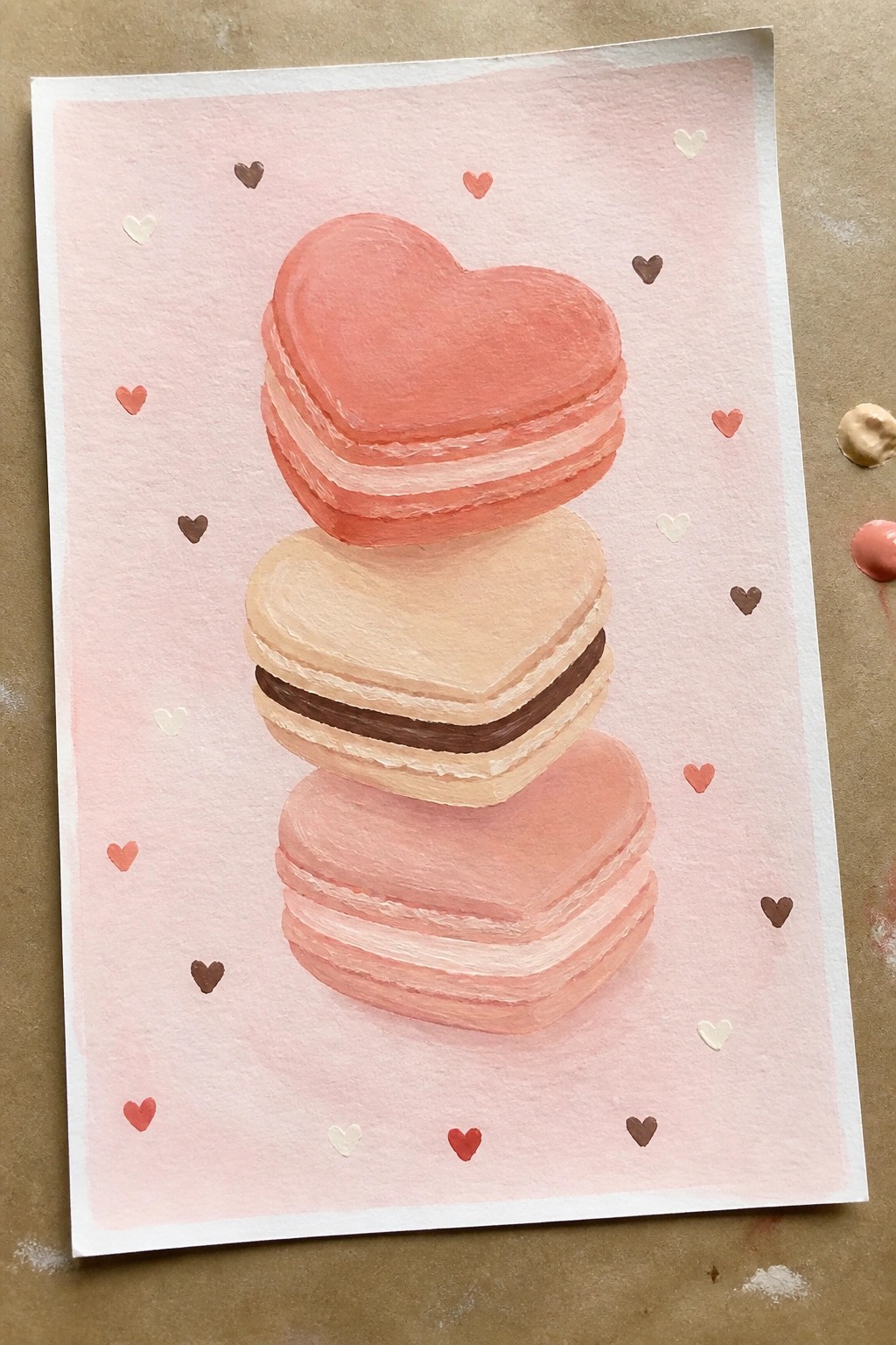 Stacked pink and beige heart-shaped macarons in watercolor style with scattered tiny hearts.