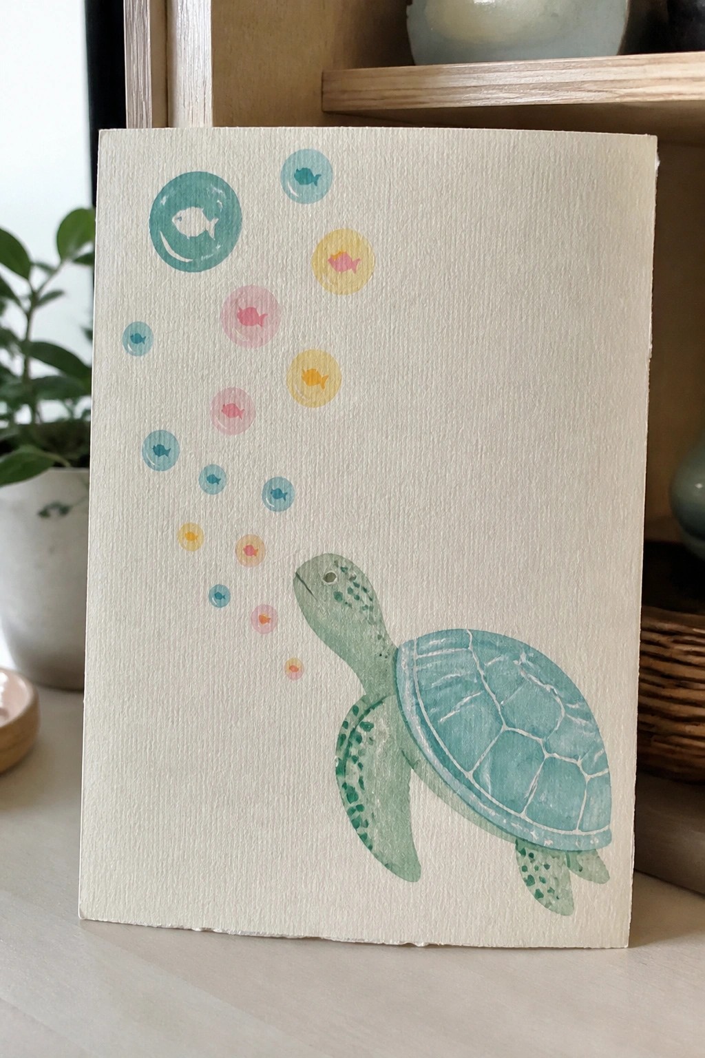 Watercolor sea turtle with colorful fish-filled bubbles rising from its mouth on textured paper