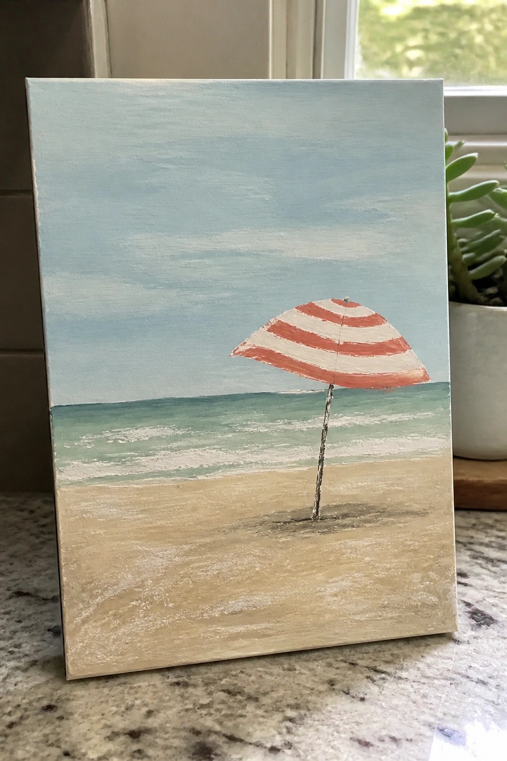Painting of red-and-white striped umbrella on sandy beach with ocean waves and blue sky