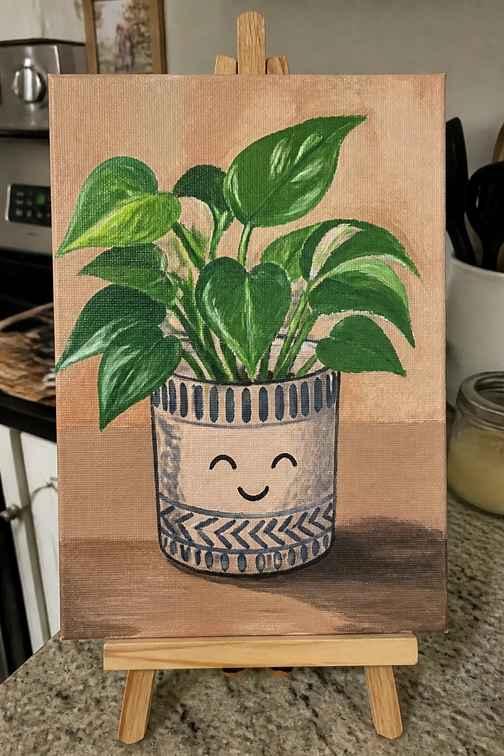 Painting of smiling potted plant with green leaves on wooden easel in kitchen