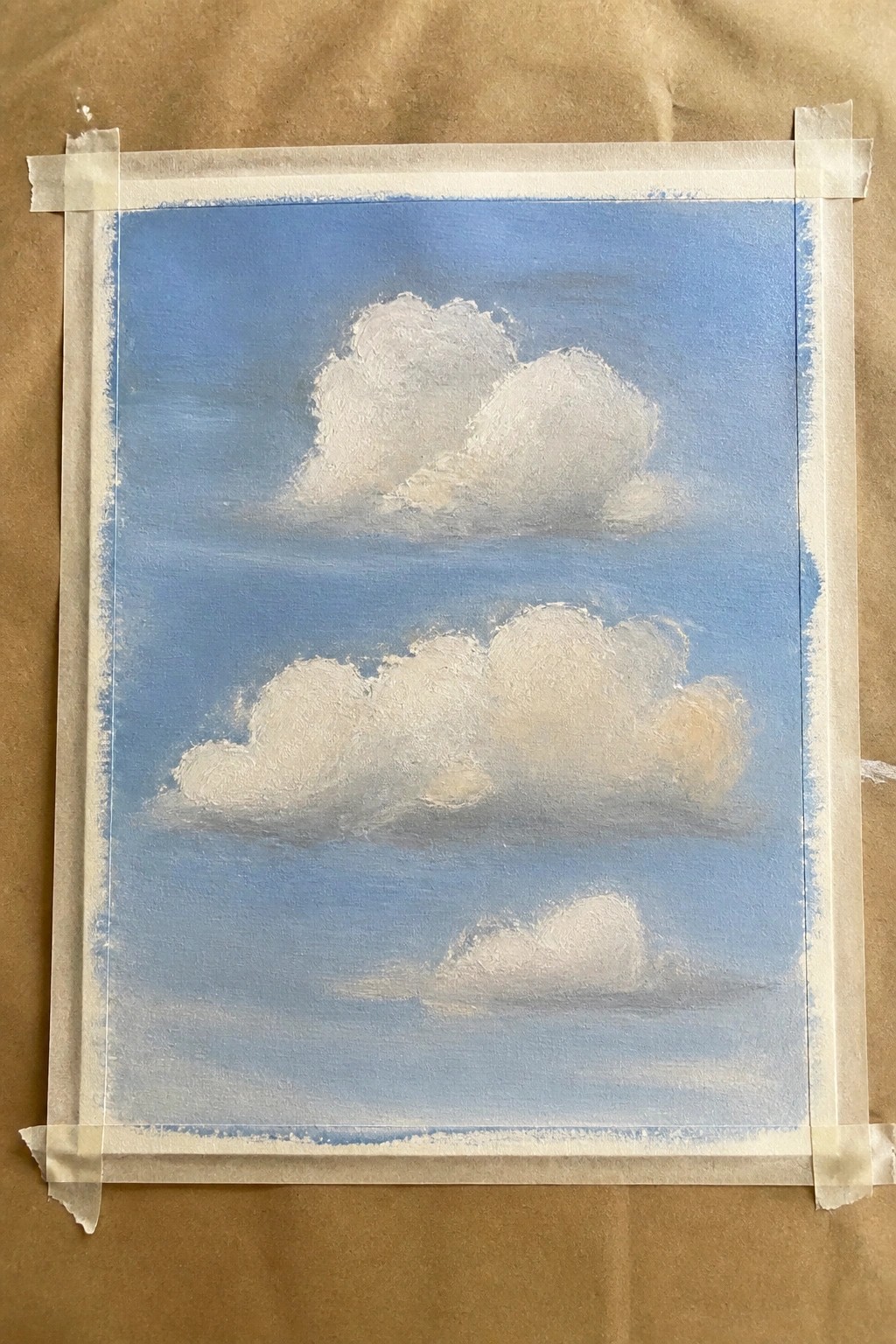 White cumulus clouds on blue sky, canvas taped to brown paper