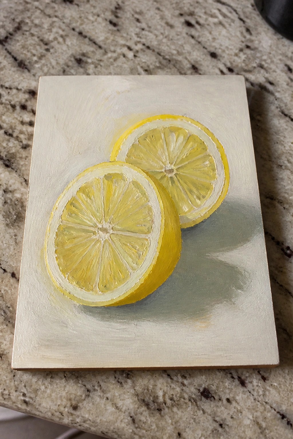 Two yellow lemon slices painted on light canvas atop marble countertop