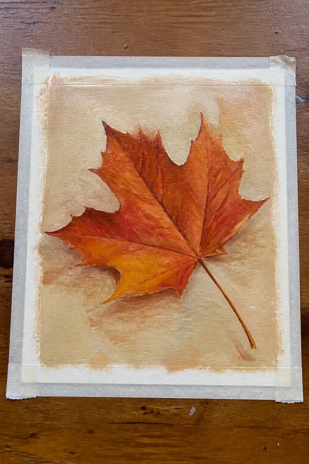 Vibrant orange-red maple leaf painting on beige paper with masking tape borders.