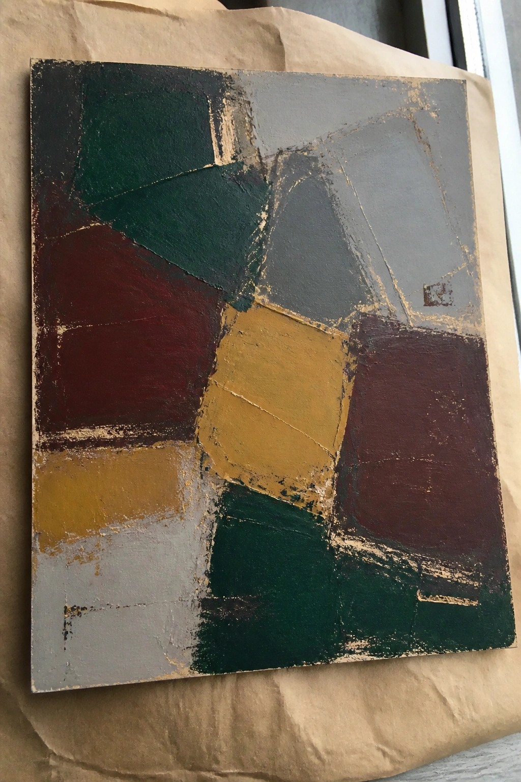 Abstract geometric painting with dark green, maroon, yellow, and gray shapes on canvas