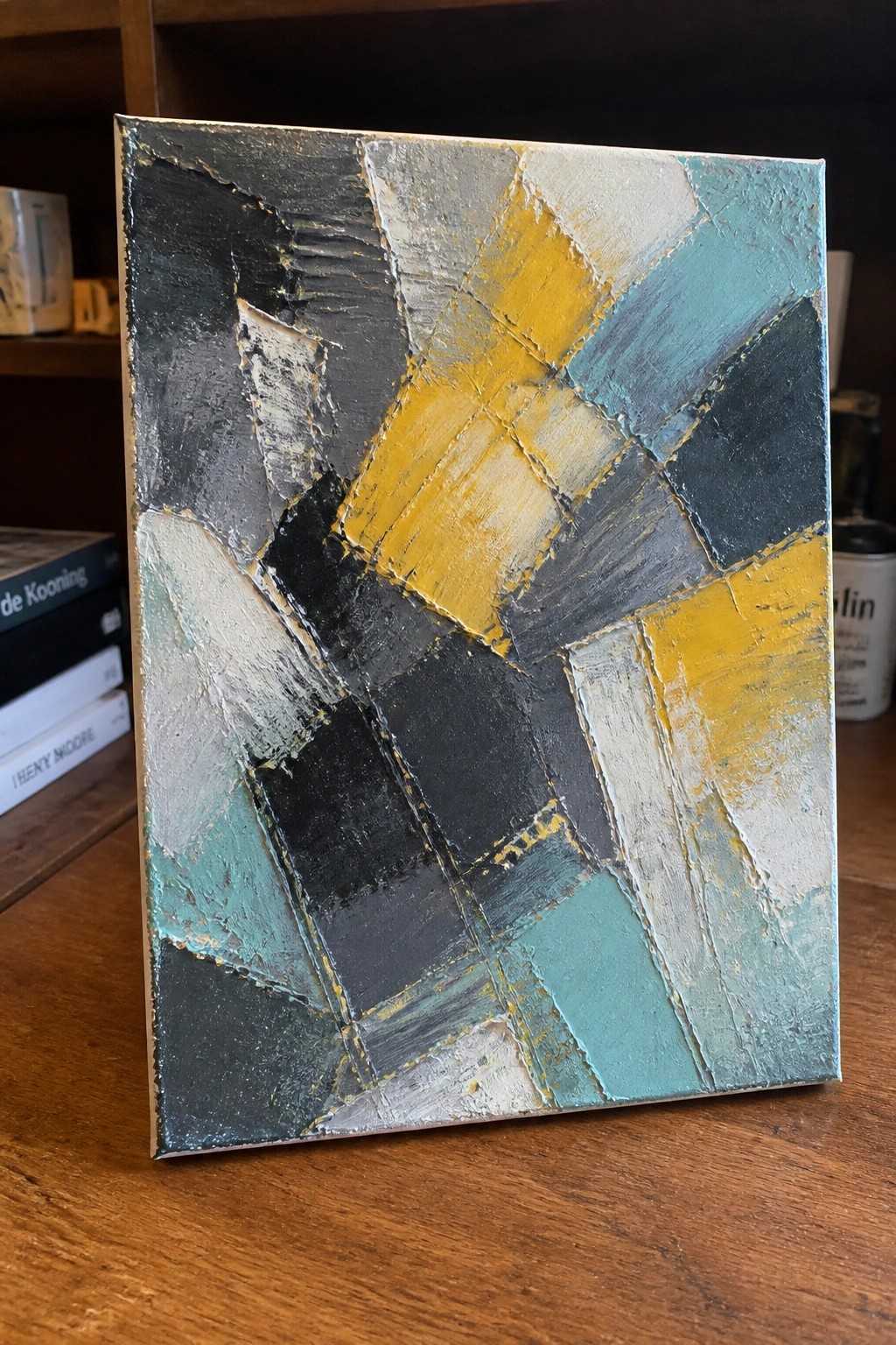 Abstract geometric painting with textured yellow, teal, black, gray, and white shapes.