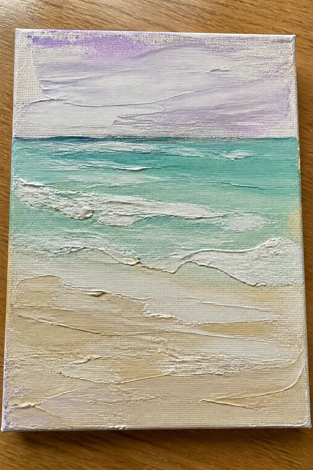 Textured seascape painting with teal waves, white foam, beige sand, and purple sky