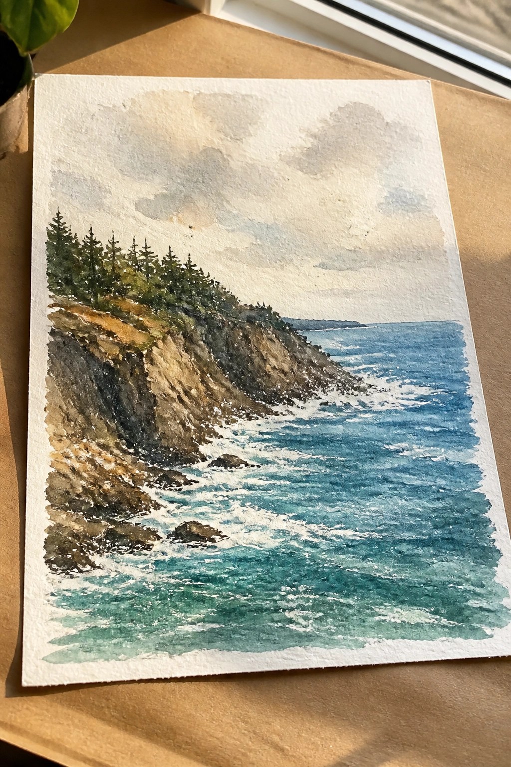 A watercolor painting of a rocky cliff with evergreen trees overlooking a blue ocean with white waves under a cloudy sky.