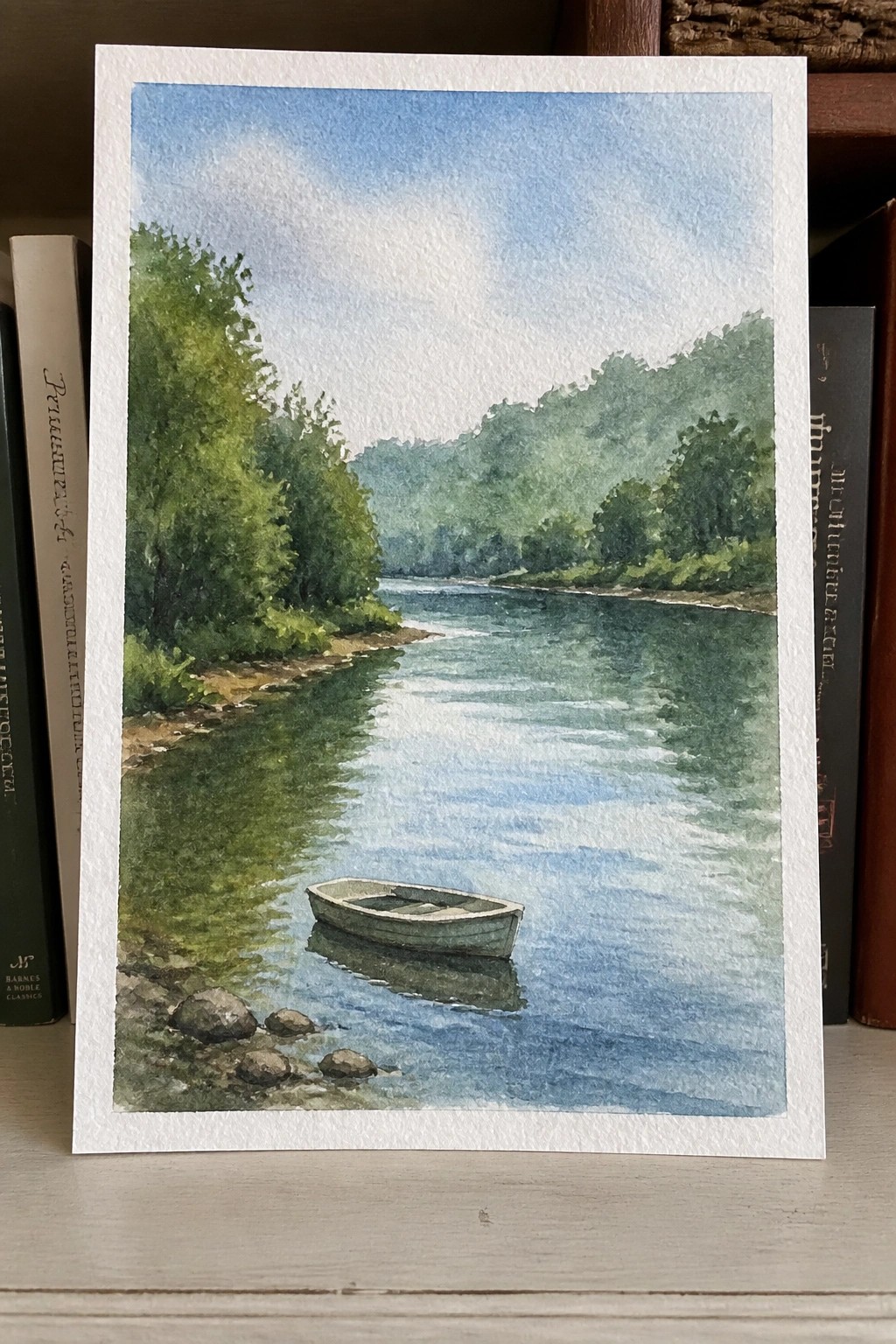 Watercolor of a small boat floating on a calm river with green hills and trees.