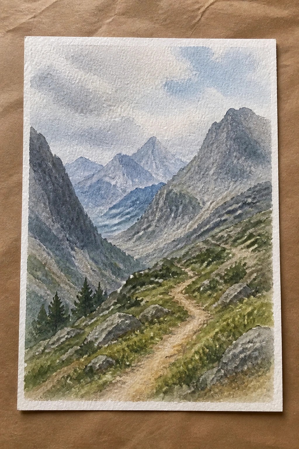 Watercolor of winding trail through green rocky mountains with distant peaks under clouds
