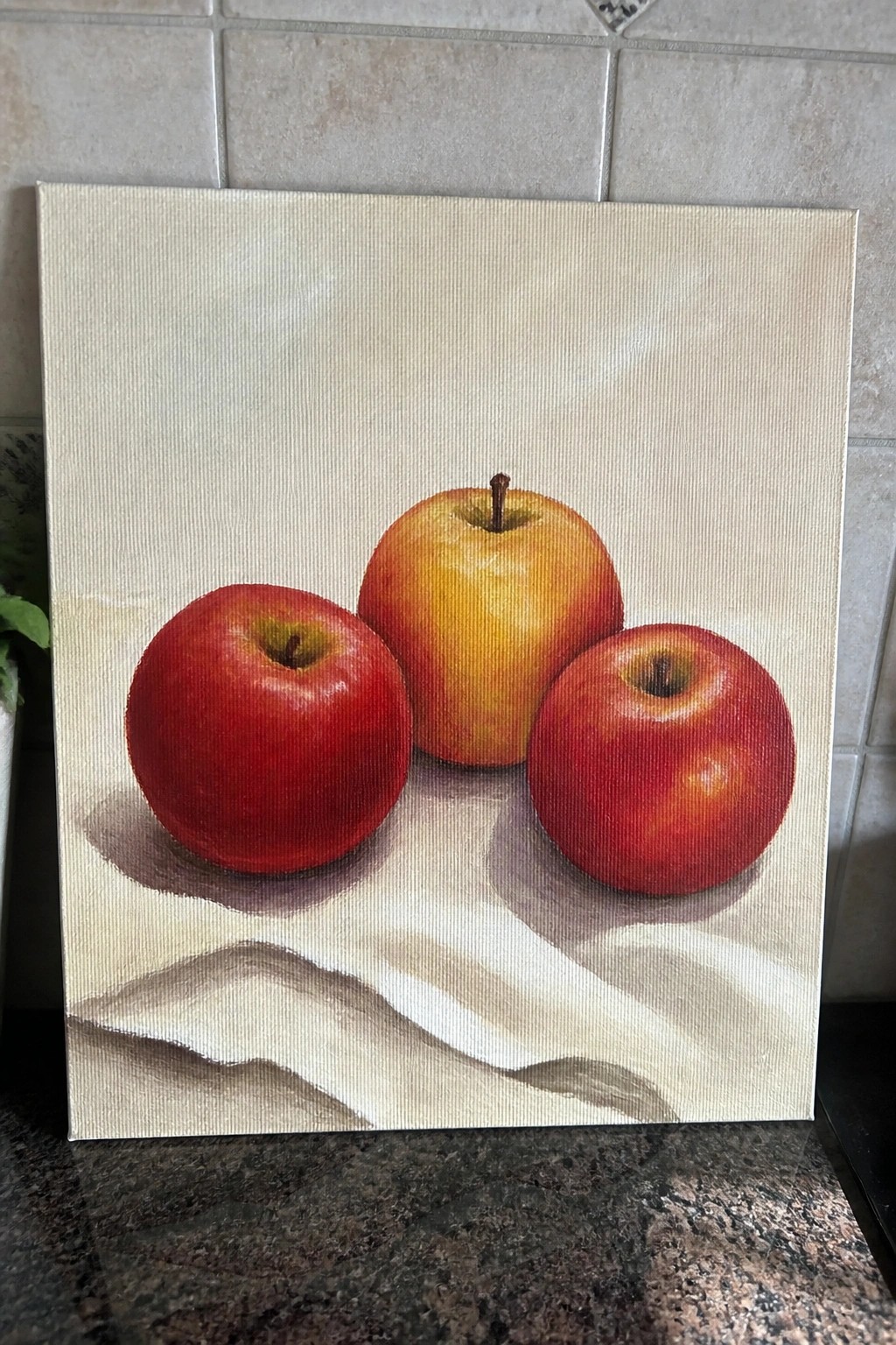 Still life painting of two red apples and one yellow apple on white cloth