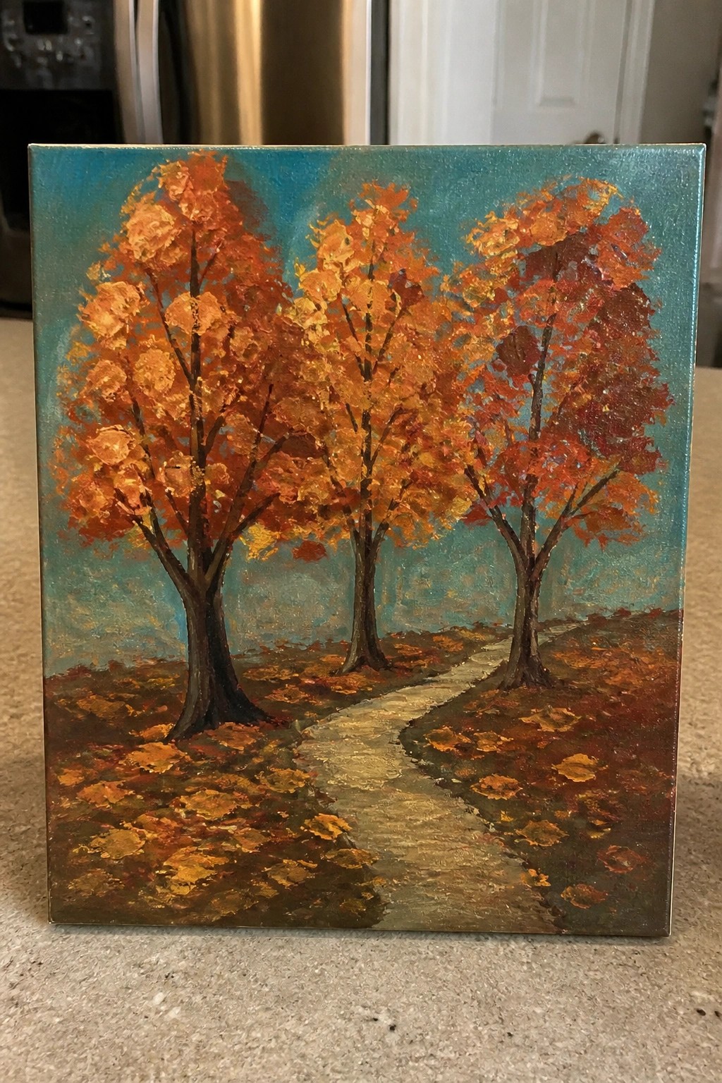 Textured autumn painting showing three orange-leafed trees beside a winding leaf-strewn path.