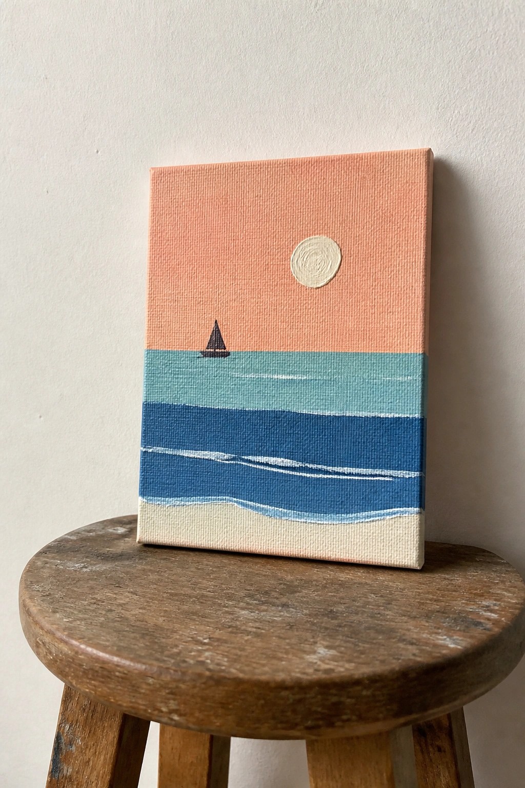 Minimalist painting of sailboat on striped blue ocean under peach sky on wooden stool
