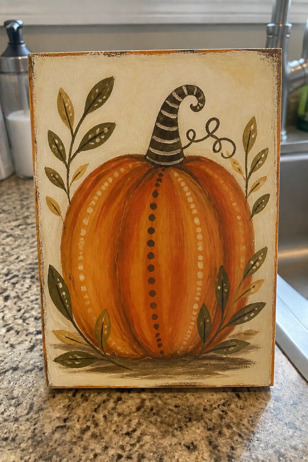 Orange pumpkin with striped stem, dotted lines, and green leaves on canvas