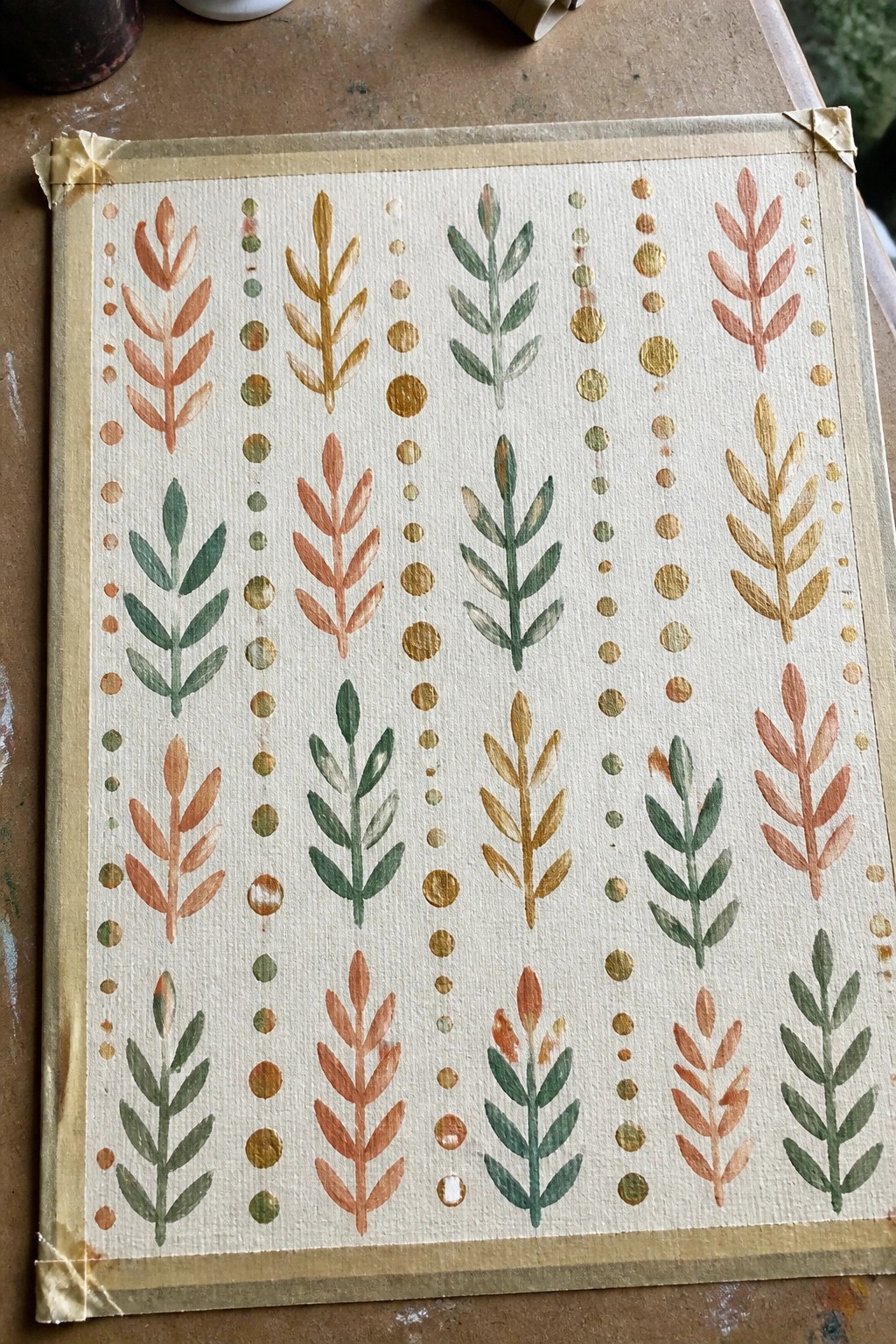 Watercolor pattern of leafy stalks in orange, green, and gold with dotted lines on paper