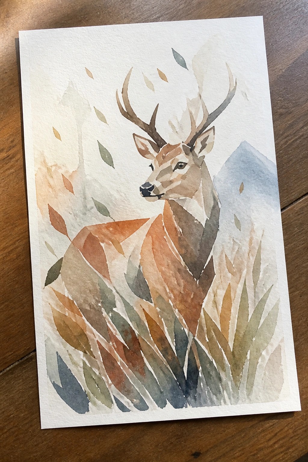 Watercolor painting of a deer with antlers amid autumn leaves and misty mountains.