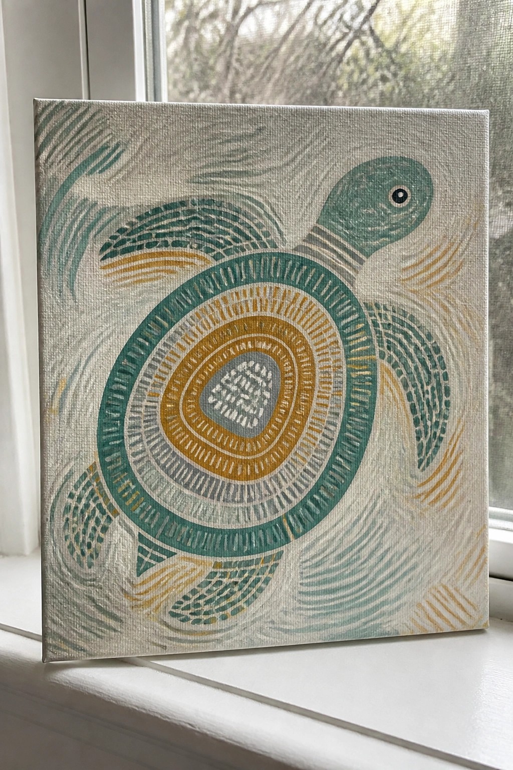 A square canvas shows a sea turtle with a shell formed by concentric circles in teal, mustard, and gray, set on a white windowsill.