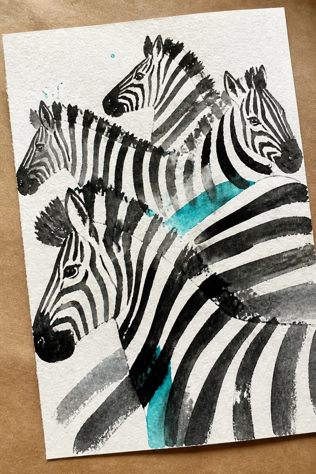 Three overlapping zebras in black-and-white stripes with teal watercolor accents on torn paper.