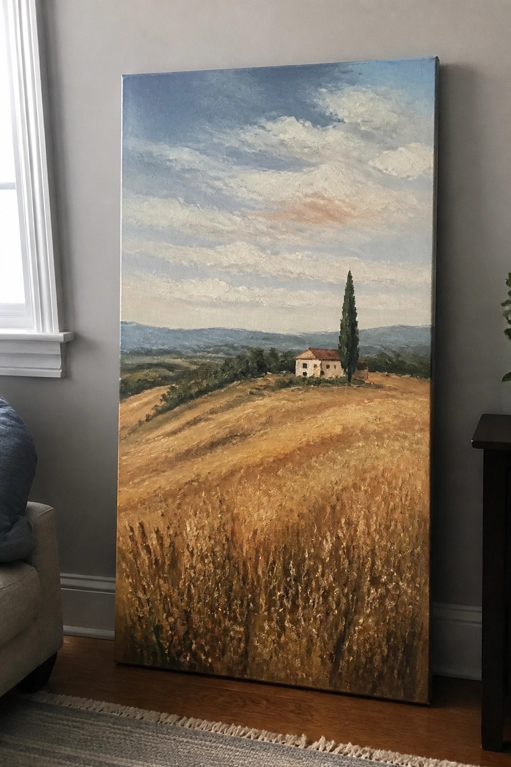 Large landscape painting of golden wheat field, house, and cypress tree in room