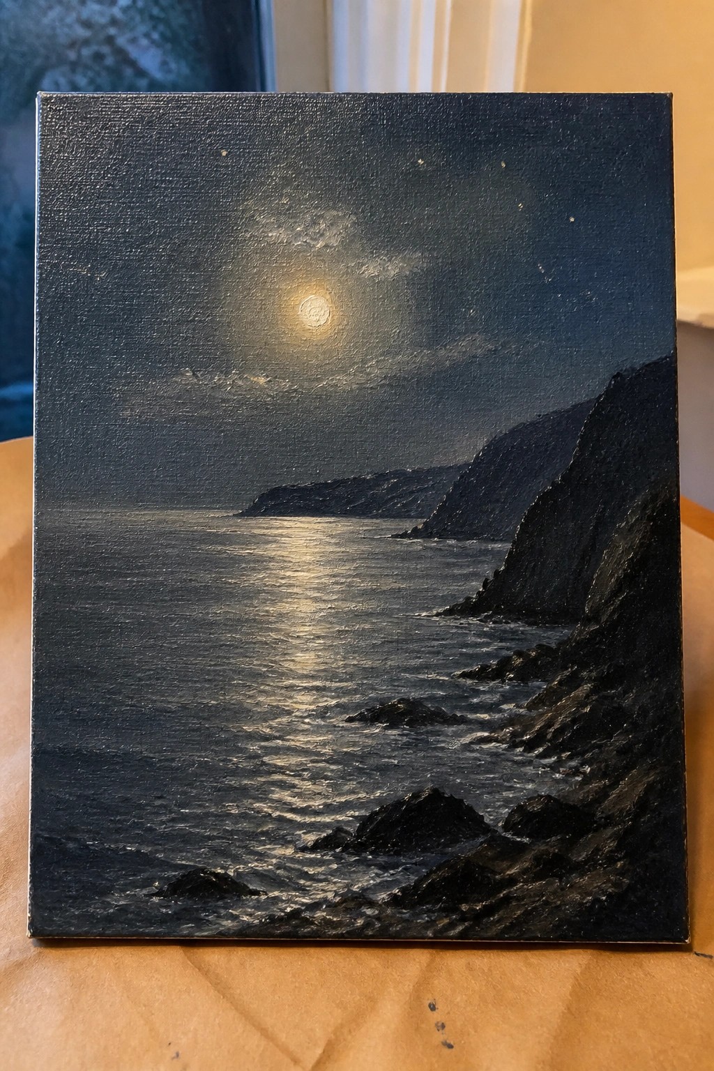 Moonlit ocean painting with full moon reflecting on waves beside dark cliffs