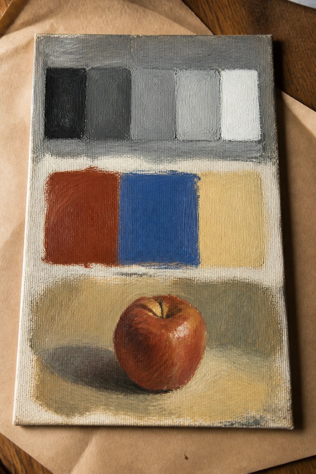 Still life painting of red apple below grayscale scale and color blocks on canvas