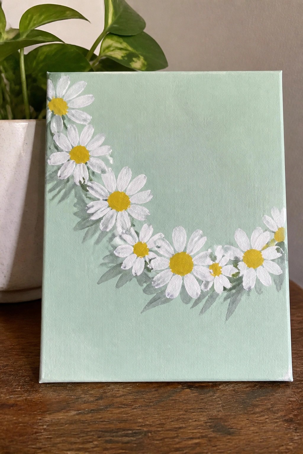 Light green canvas with white daisies and yellow centers curving across it