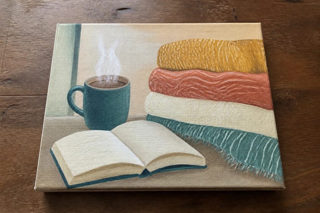 Painting of steaming teal mug and open book on colorful wavy striped blanket
