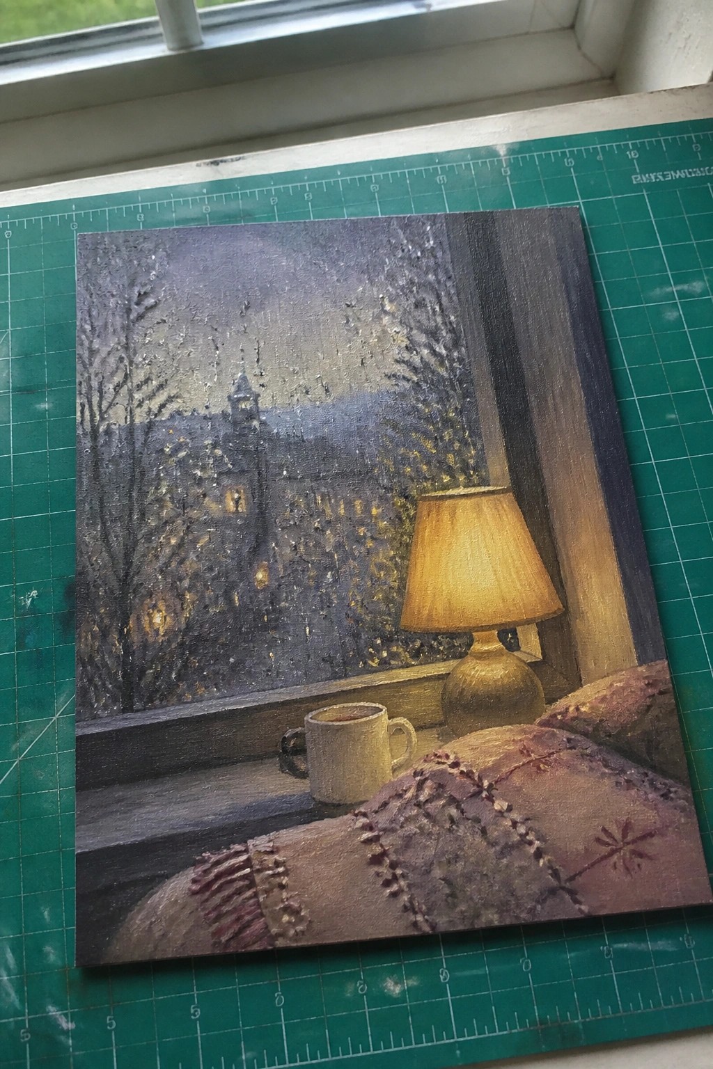 Cozy bedroom scene with lamp, mug, and snowy town view through window at night