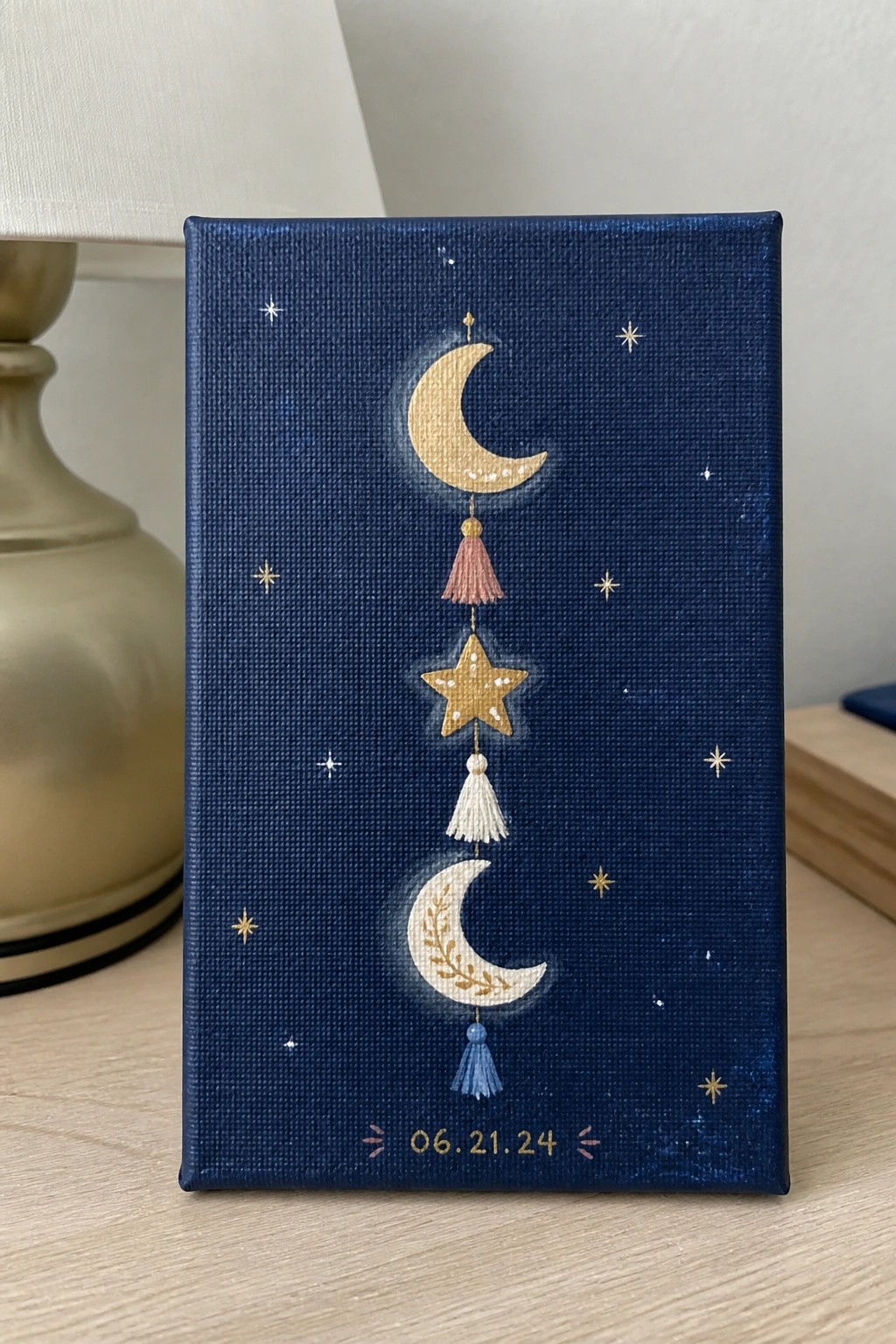 Navy canvas painting with two crescent moons, gold star, tassels, and scattered stars