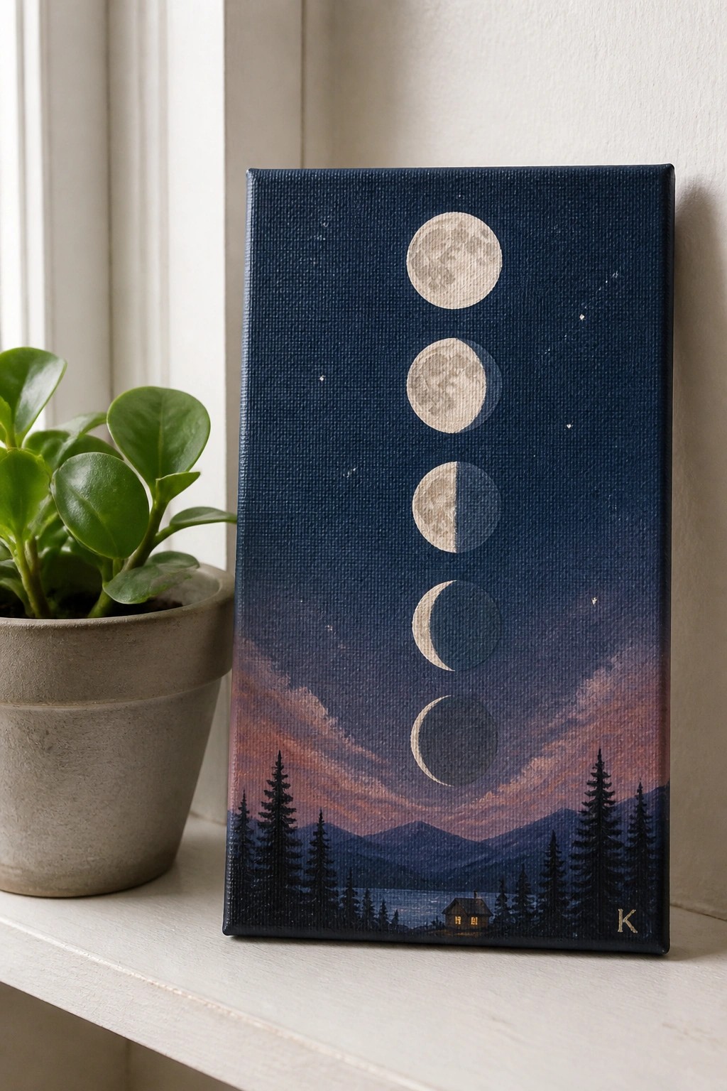 Painting of moon phases over mountain cabin landscape beside potted plant on sill