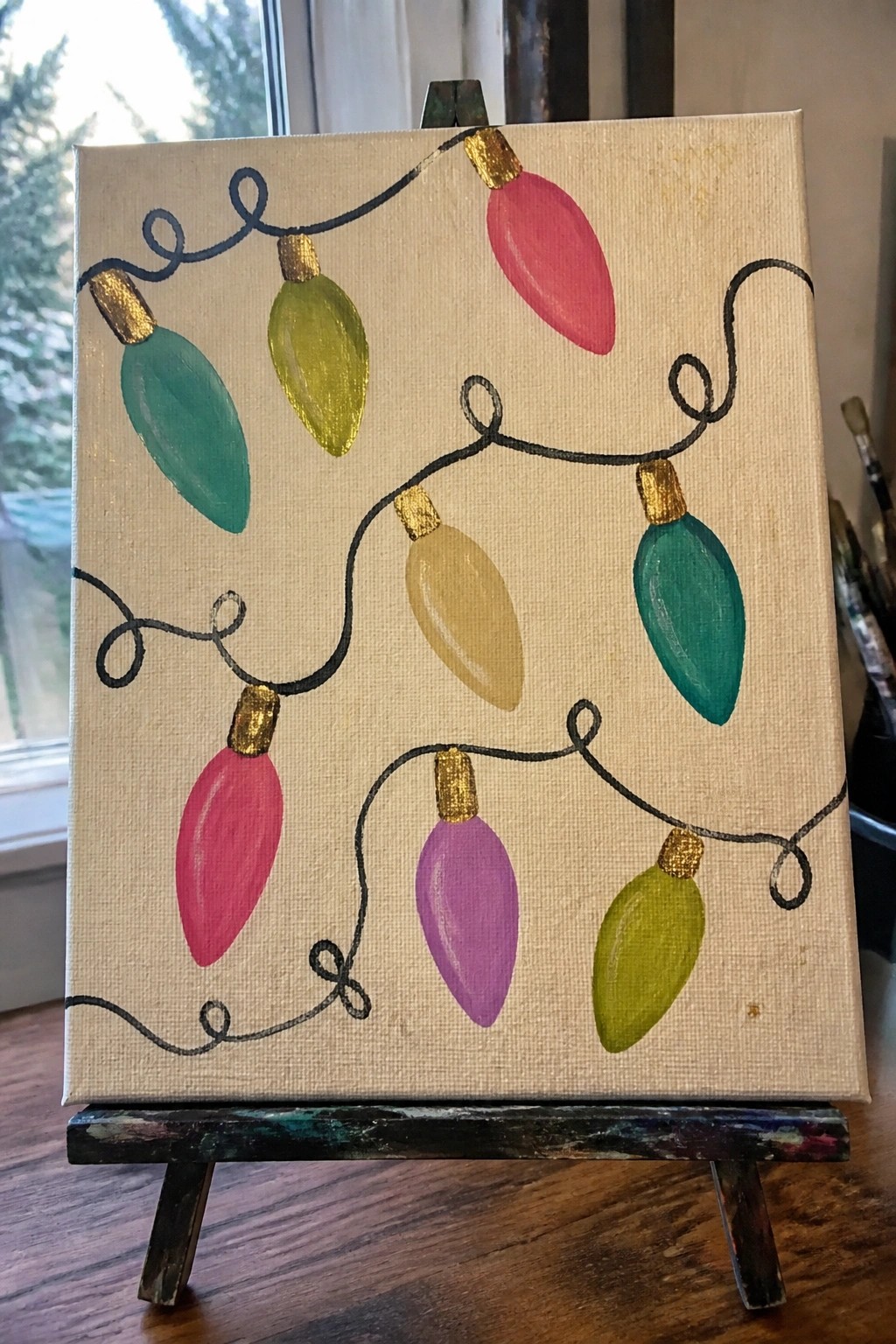 Canvas painting of colorful Christmas lights in pink, green, yellow, purple on easel