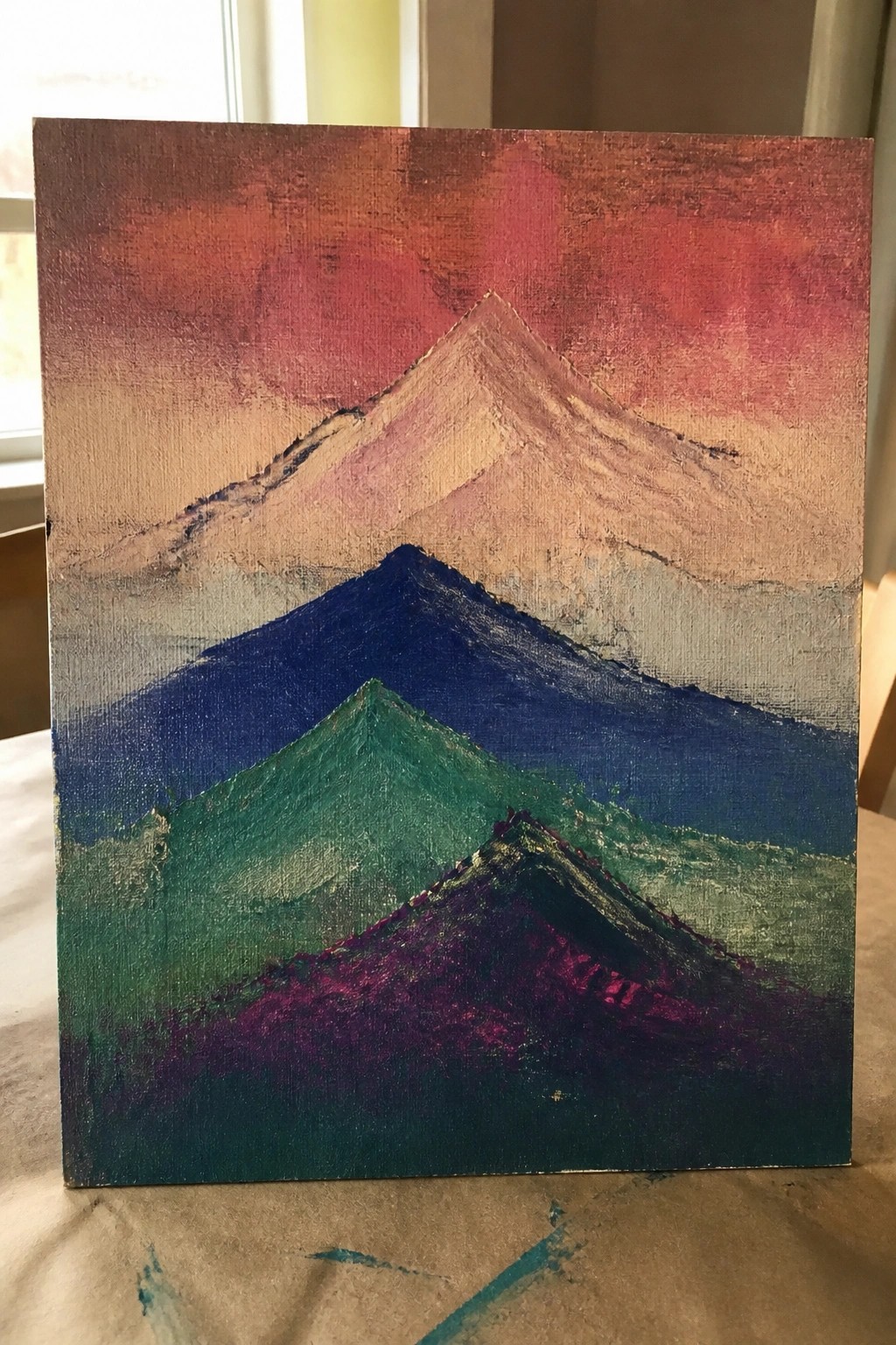 Colorful abstract painting of layered mountains under a red-pink sunset sky.