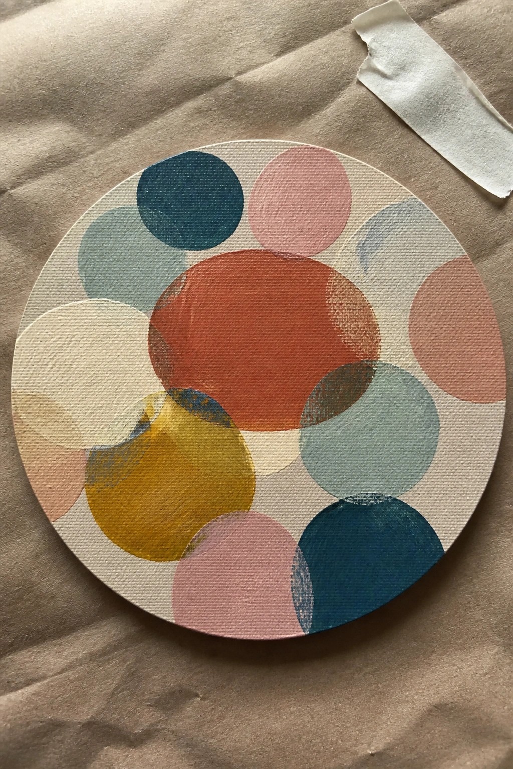 Circular canvas with overlapping colorful circles on brown fabric.