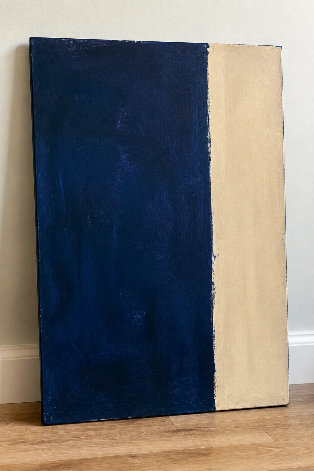 Large abstract painting split vertically into dark blue and beige sections against wall