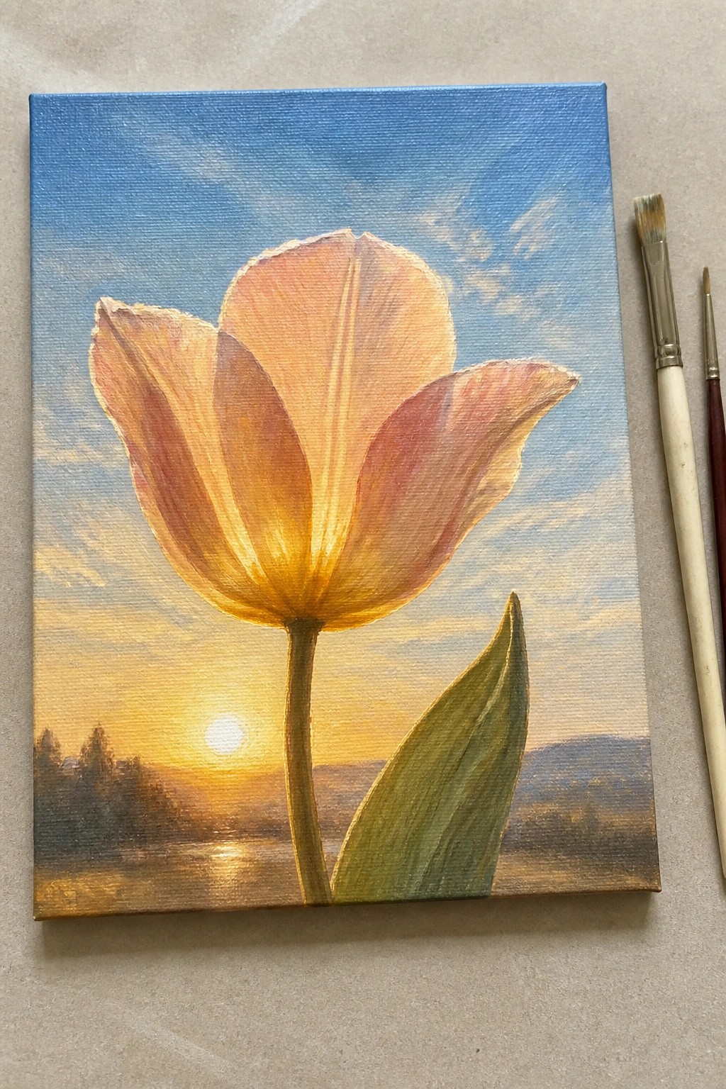 Vibrant tulip painting on canvas with sunset landscape and two paintbrushes beside it.