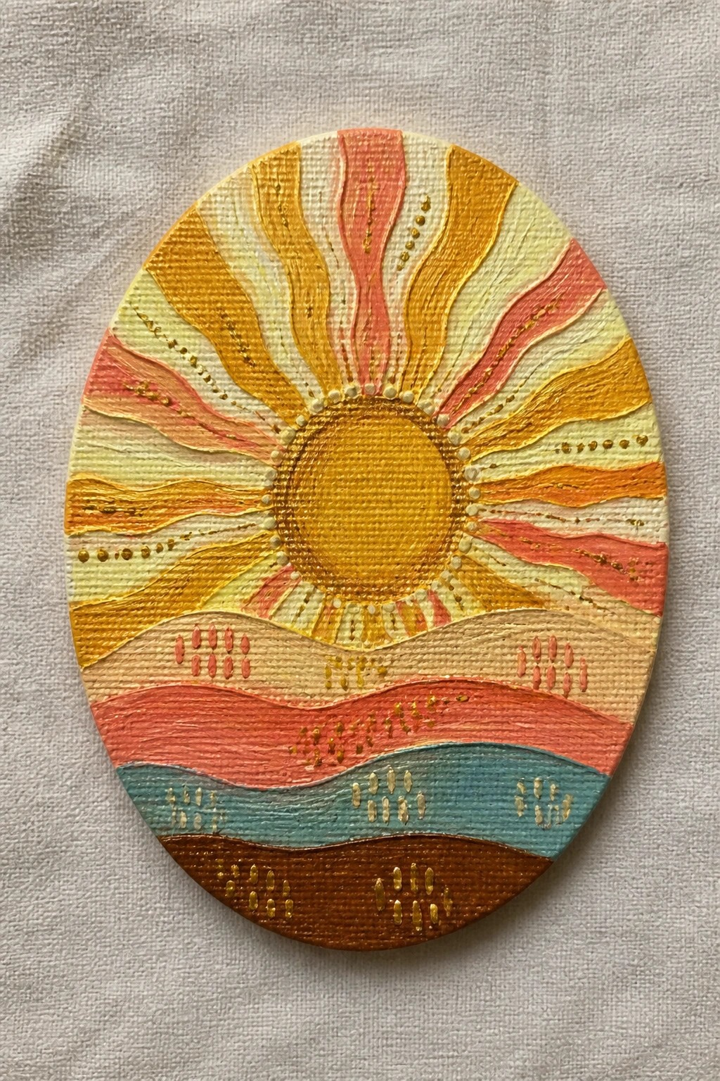Oval painting of golden sun with pink-orange rays above colorful wavy layers and dots.