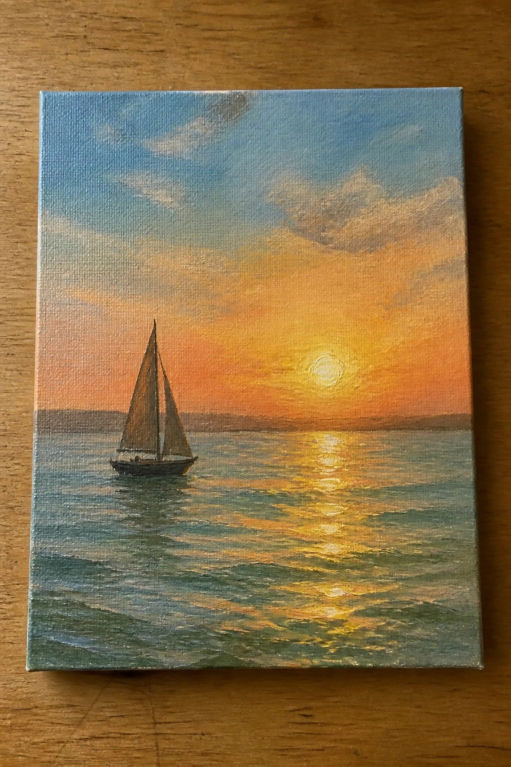 Sailboat on calm sea beneath vibrant orange sunset sky with golden reflections.