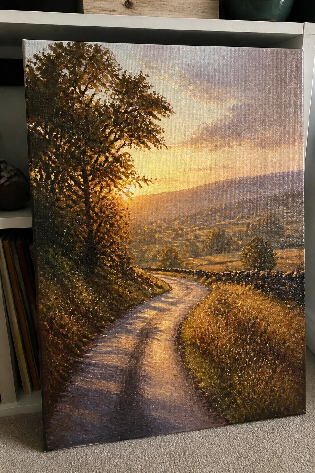 Winding country road at golden sunset with large tree, stone walls and rolling hills