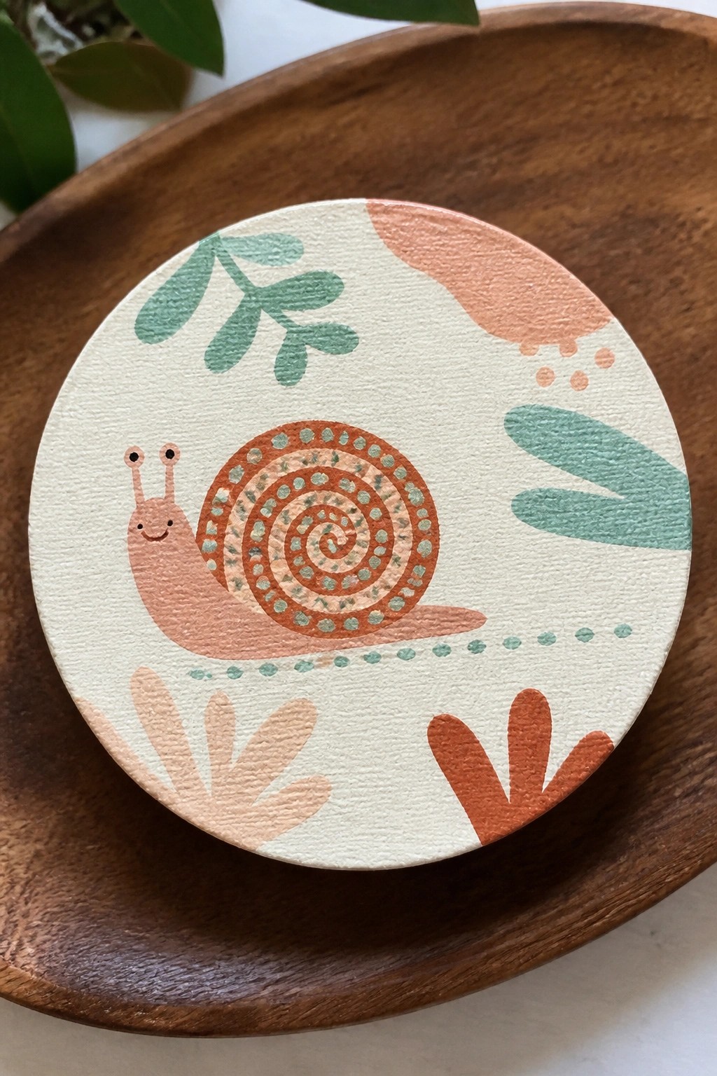 Hand-painted snail with spiral shell amid abstract coral and mint leaves on wood