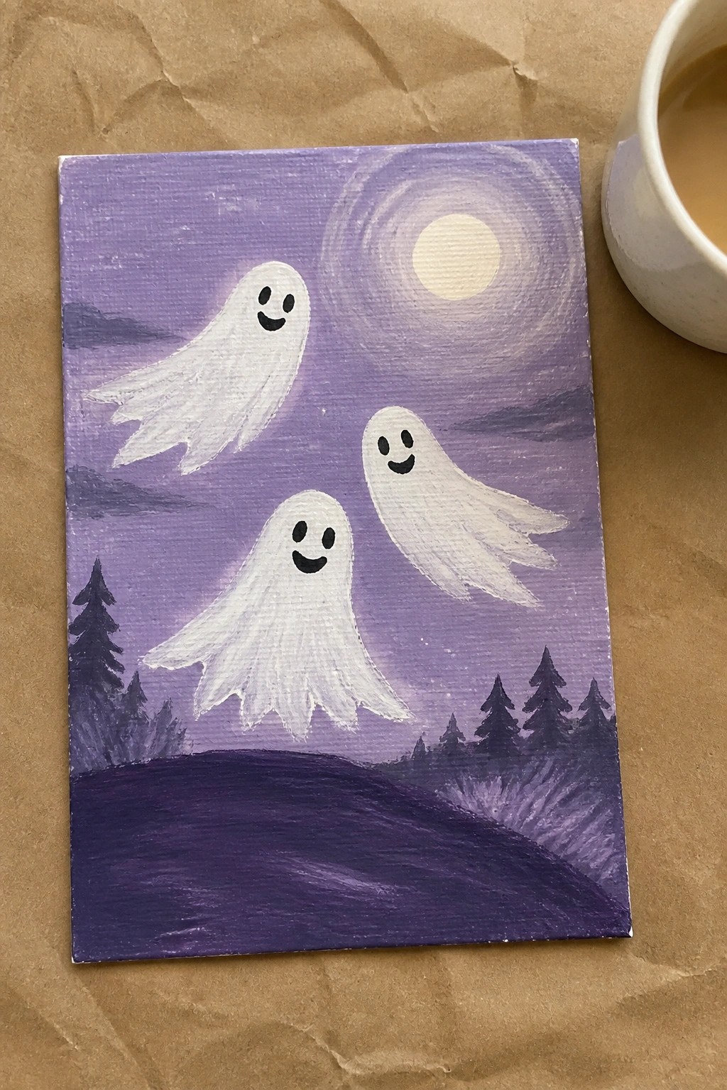 Three white cartoon ghosts with smiling faces float in a purple night sky above dark pine trees, with a glowing moon in the upper right.
