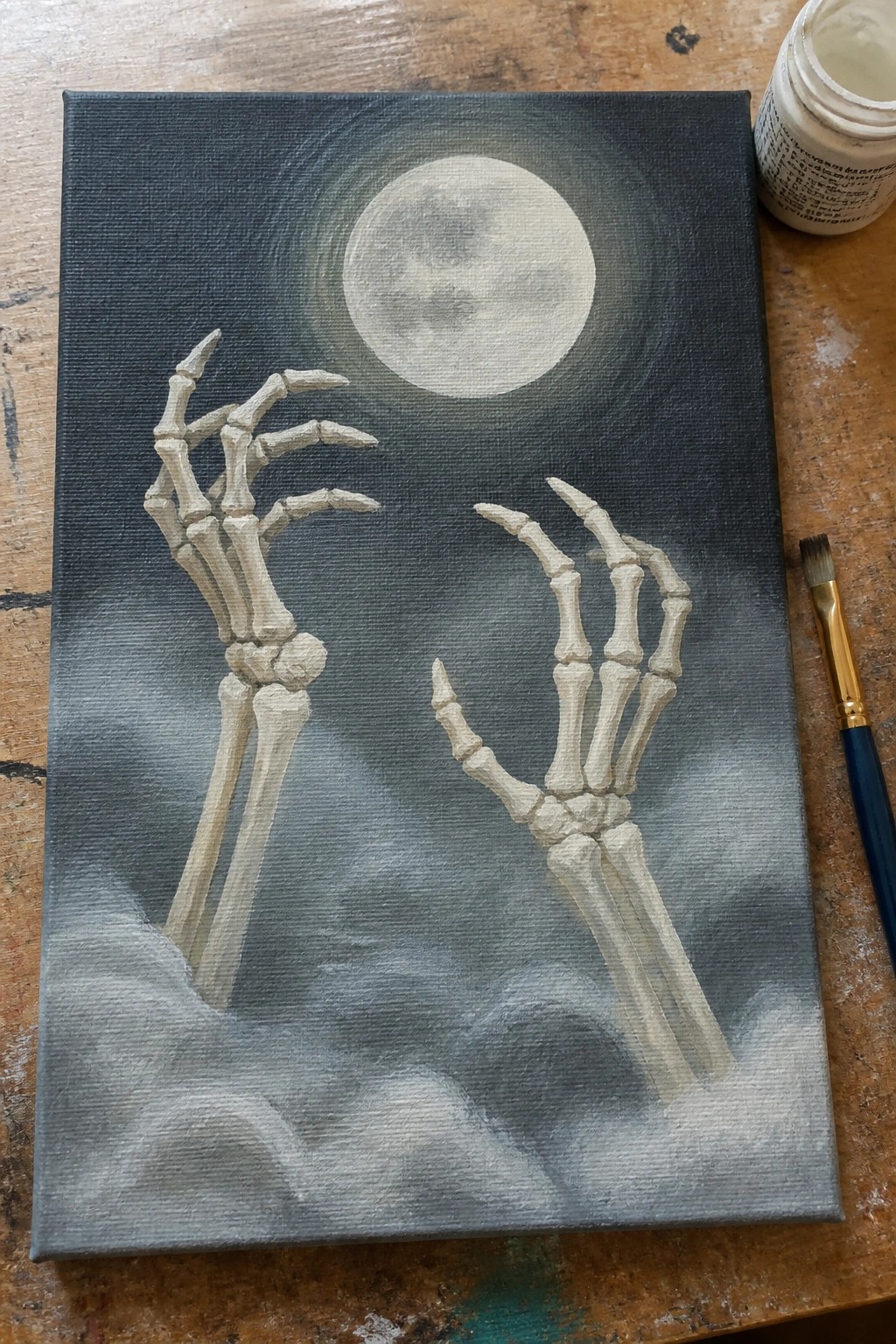 Skeletal hands reach from clouds toward a glowing full moon in dark sky painting