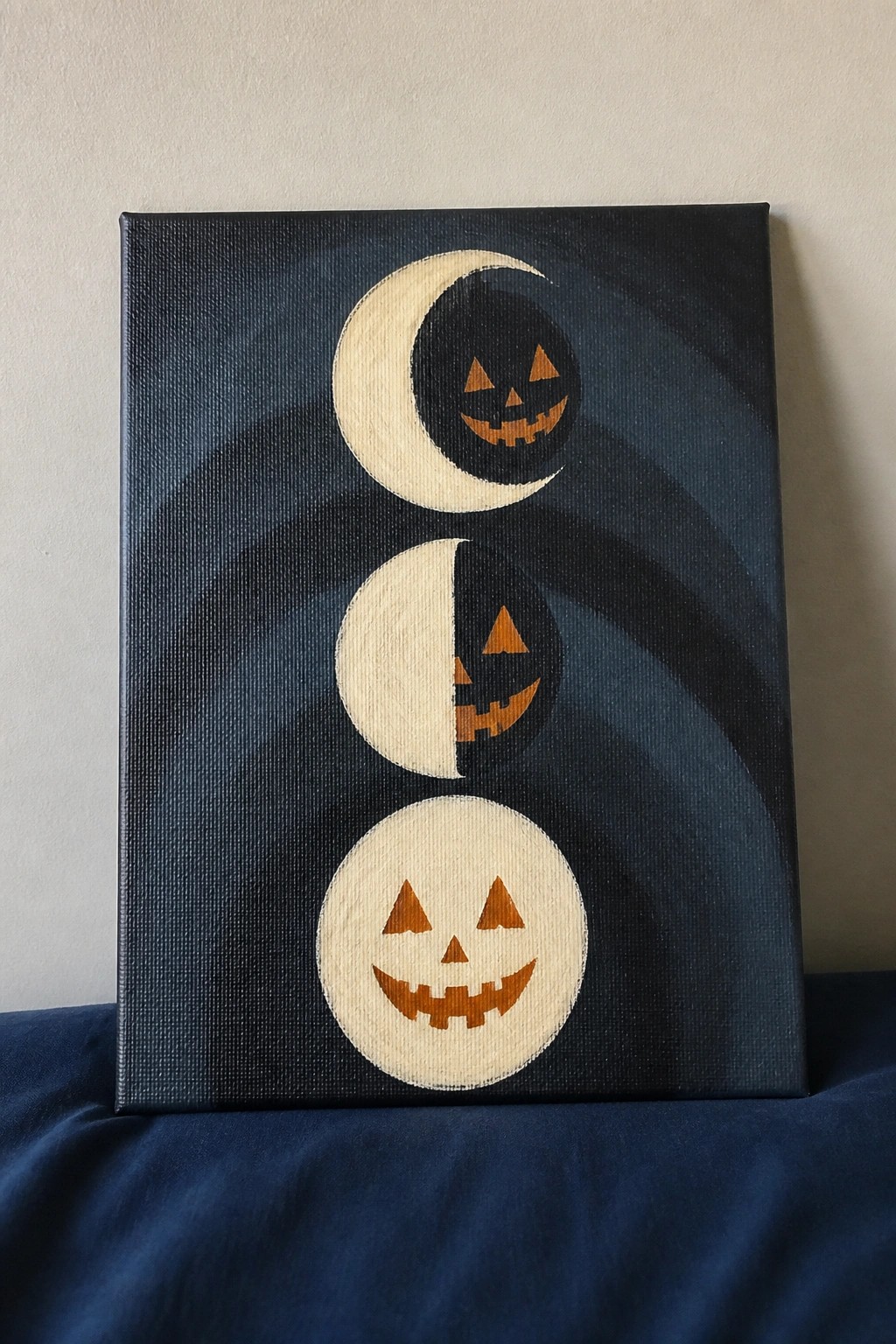 Three moon-phase jack-o'-lanterns painted on dark blue canvas with swirls.
