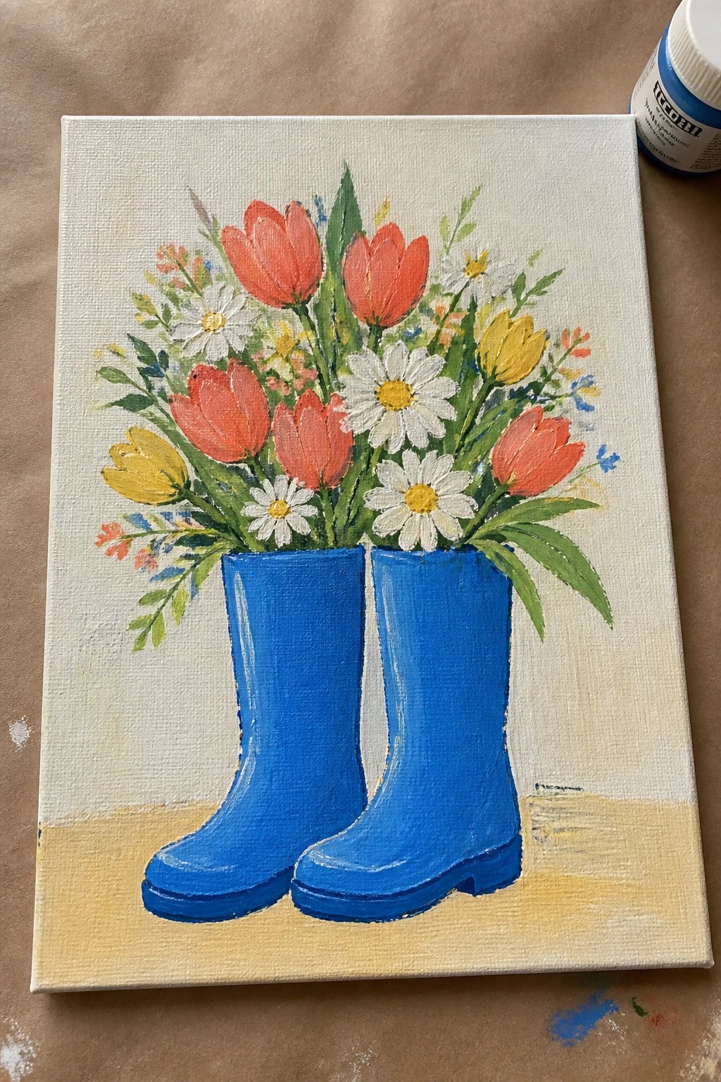 Blue rain boots filled with red tulips, yellow flowers, and white daisies in acrylic painting