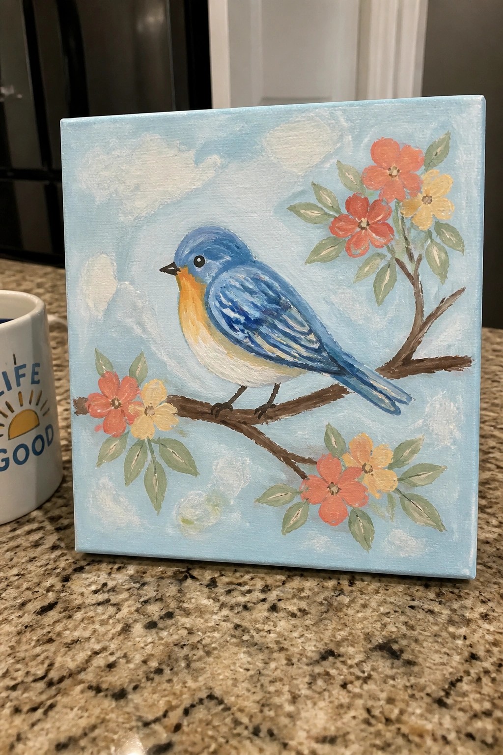Bluebird perched on branch with orange-yellow flowers against light blue sky canvas