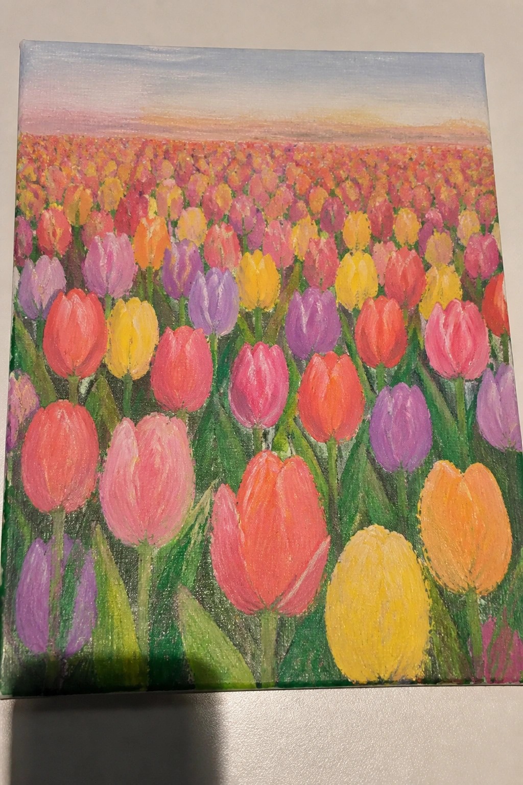 Vibrant painting of dense tulip field with pink, red, yellow, purple blooms under pastel sky.