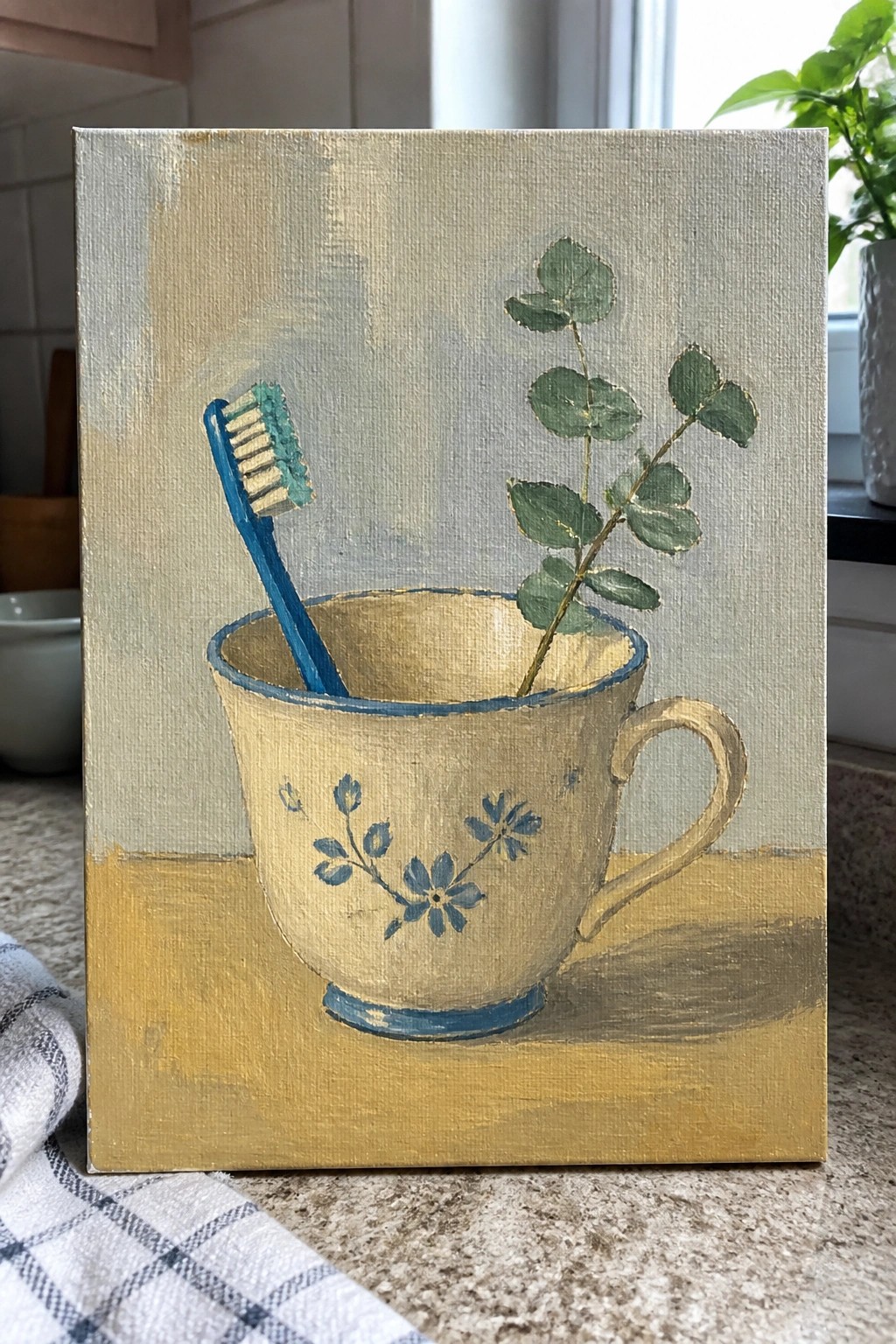Painting of a floral teacup holding a blue toothbrush and green eucalyptus sprig on gold surface