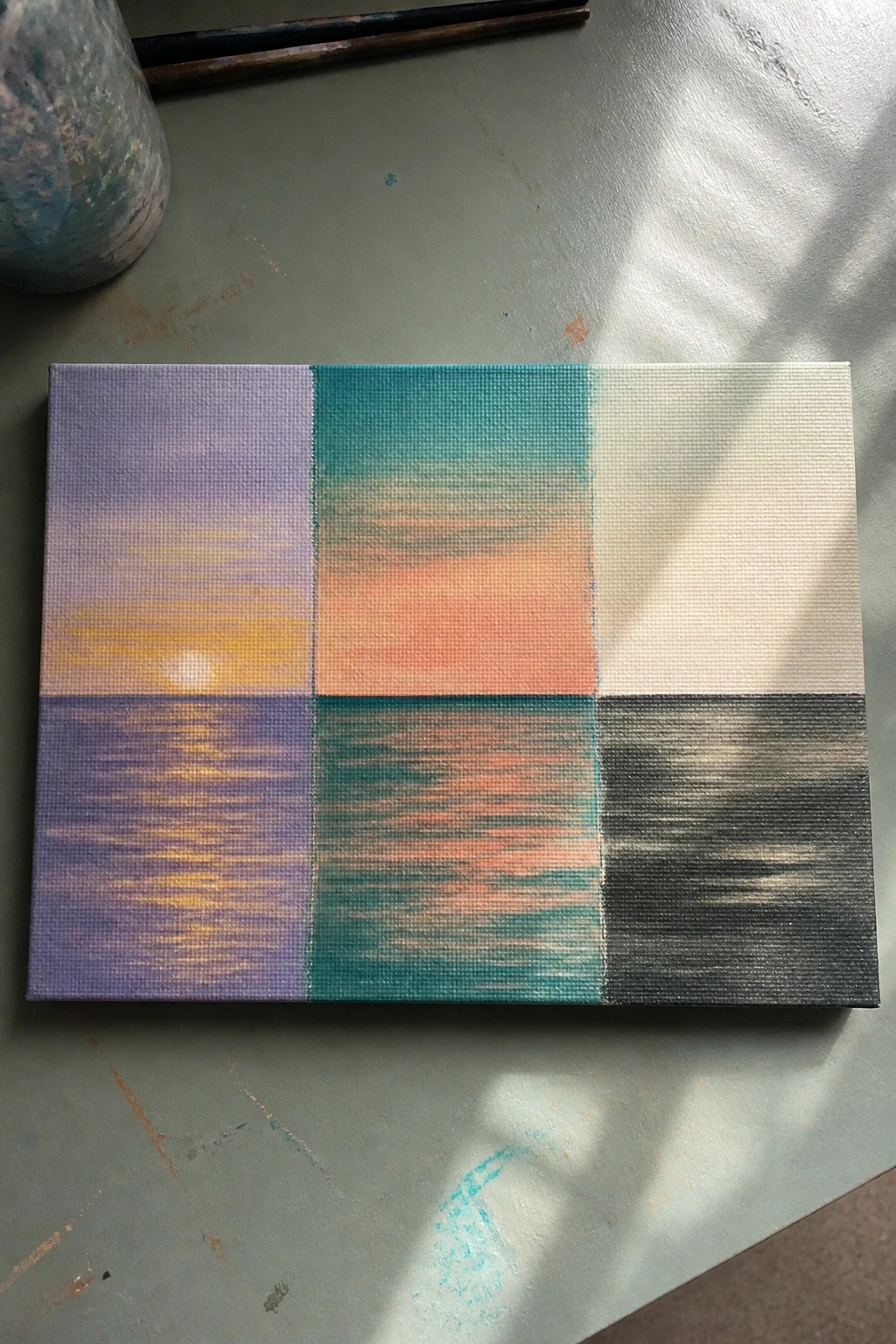 Abstract canvas divided into six colorful panels depicting sunset and water reflections on gray surface.