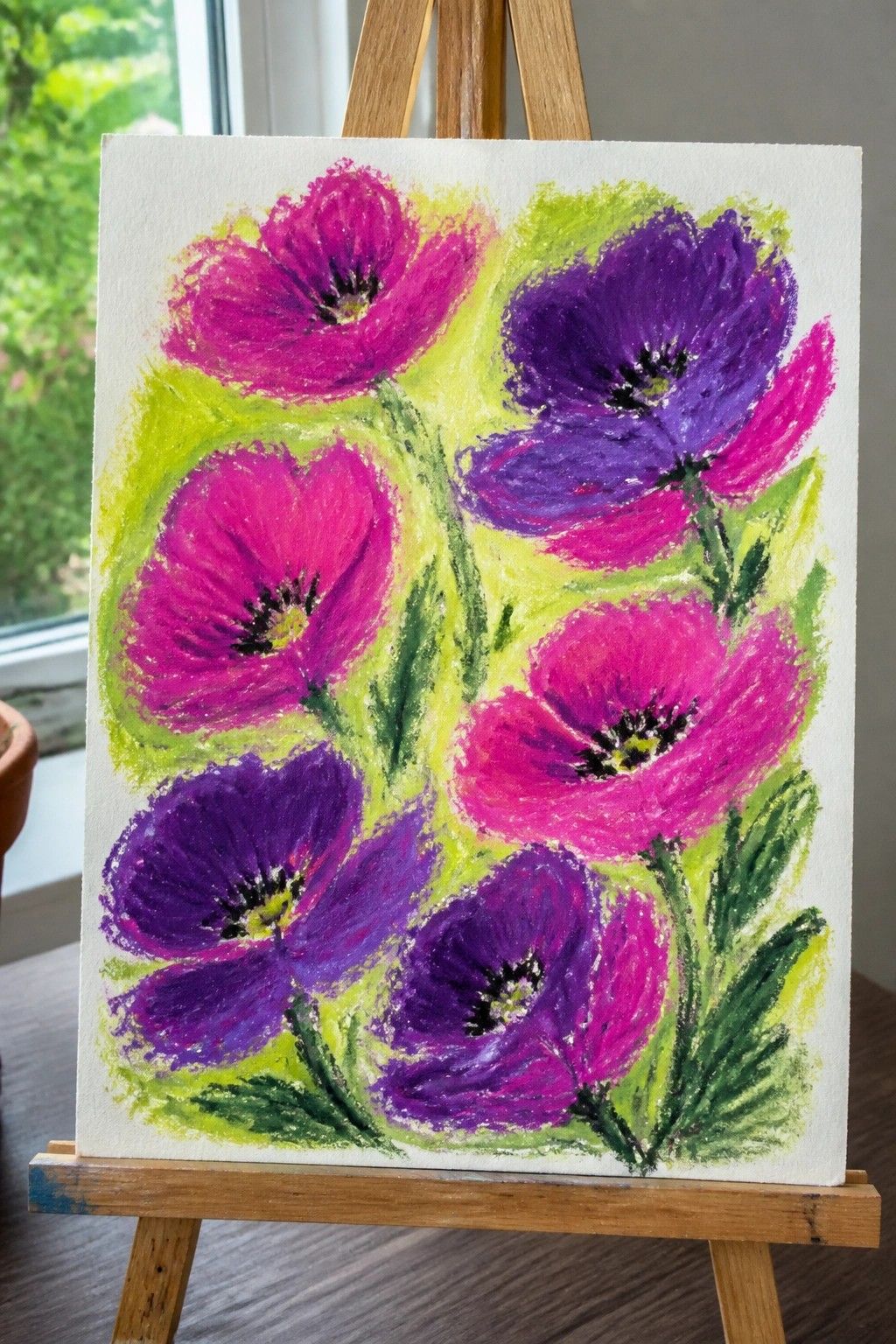 Vibrant pink and purple poppy painting on wooden easel with green foliage
